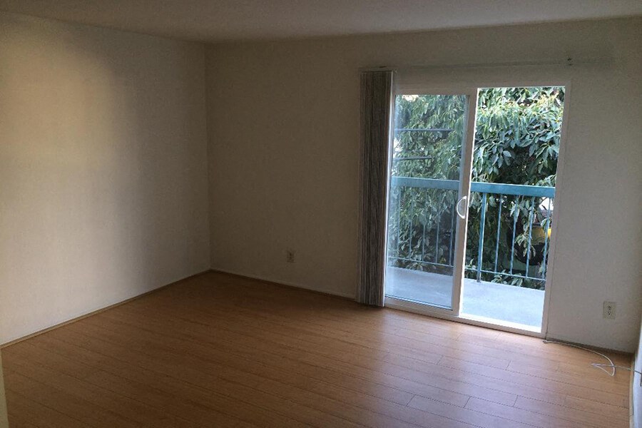 an empty living room with wood floors and a sliding glass door