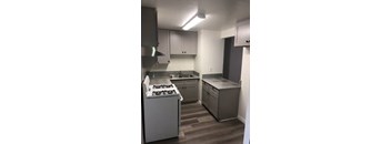 A kitchen with a white stove and grey cabinets.