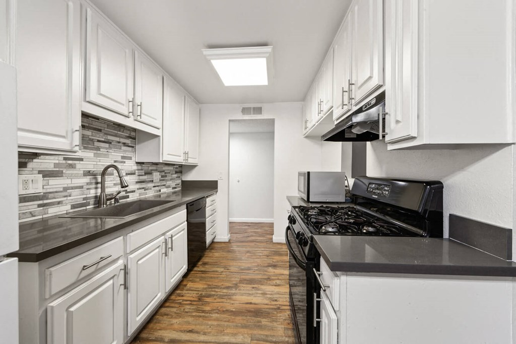a kitchen with white cabinets and black counter tops