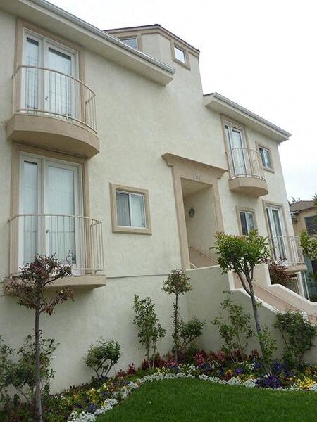 a white house with two balconies and a garden