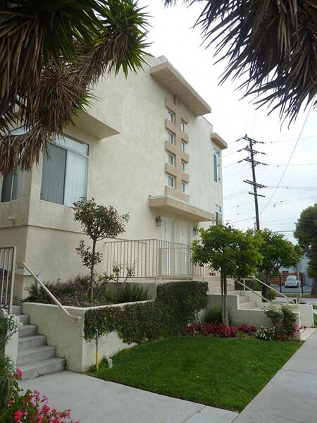 an apartment building with stairs and a garden in front of it