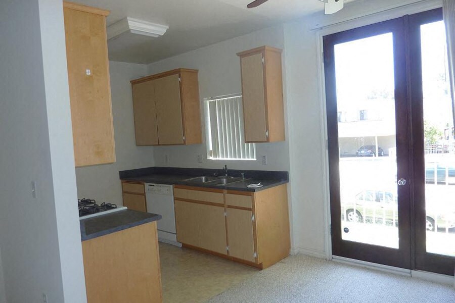 an empty kitchen with wooden cabinets and a glass door