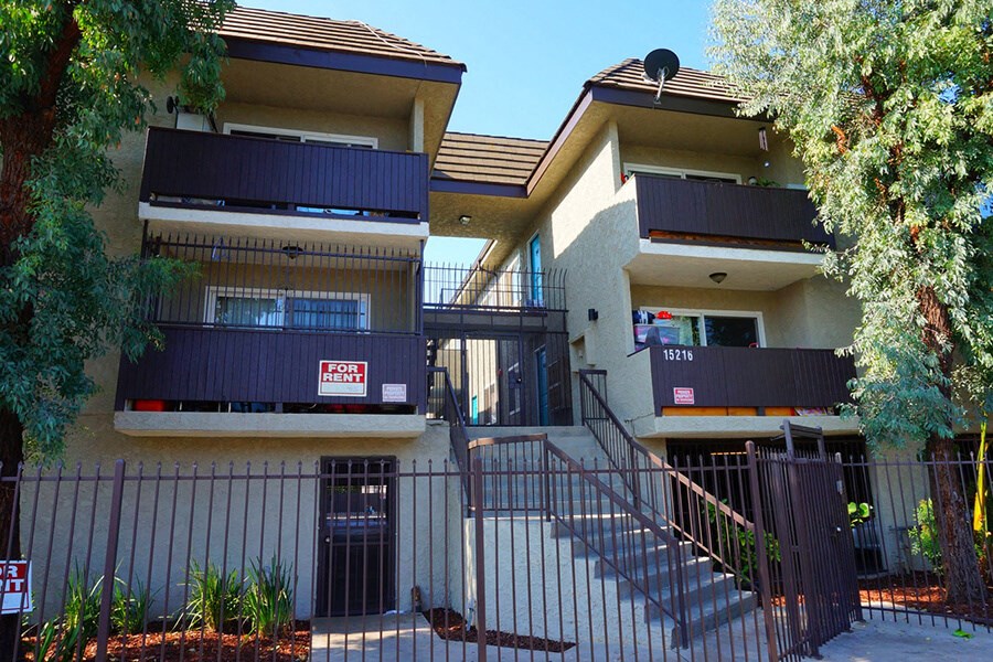 an apartment building with stairs and a fence in front of it