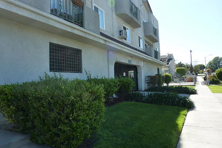 a white apartment building with a sidewalk and grass