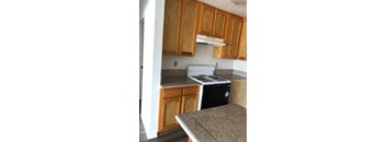 A kitchen with wooden cabinets and a white stove top oven.