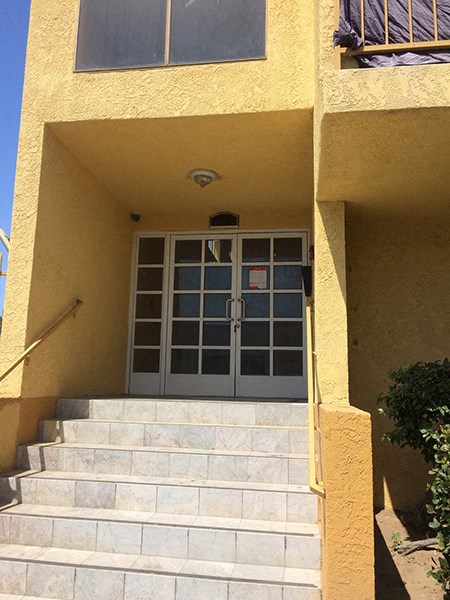 the front door of a yellow building with stairs in front of it