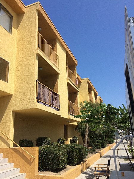 a row of yellow apartments with balconies and bushes
