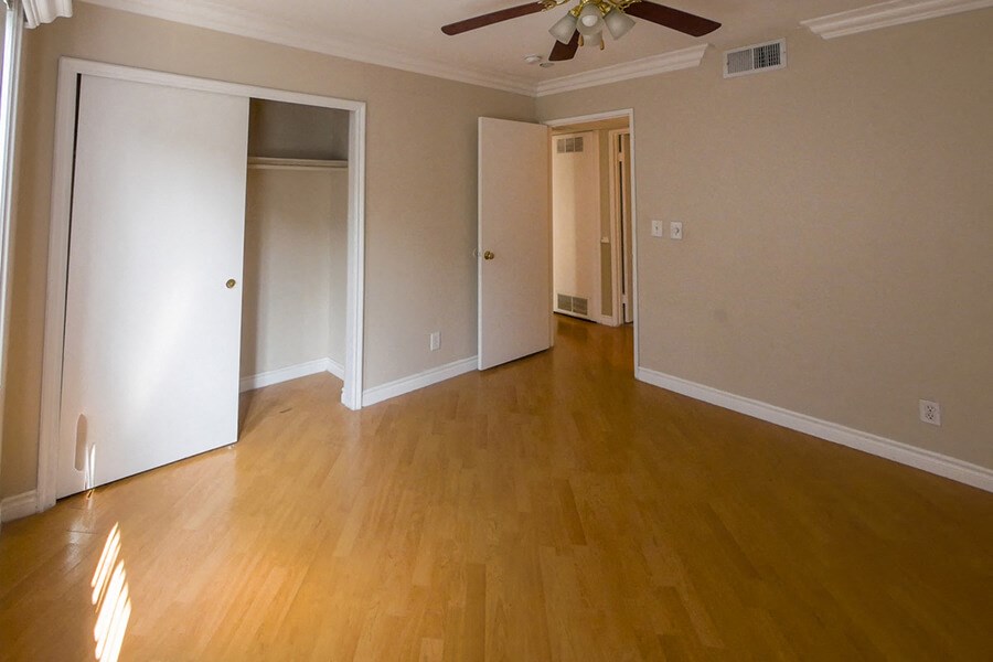 an empty living room with wooden floors and a ceiling fan