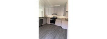 A kitchen with white cabinets and a grey floor.