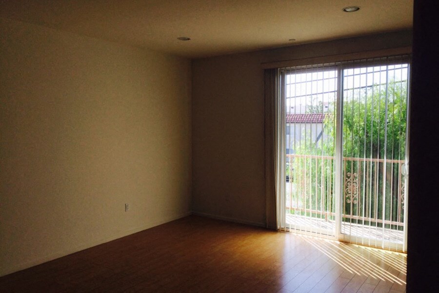 an empty living room with wooden floors and a sliding glass door