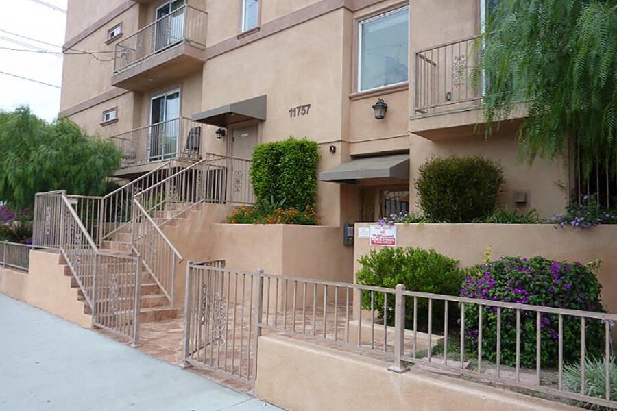an apartment building with stairs and plants in front of it