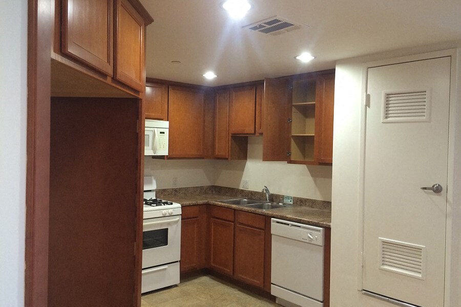 an empty kitchen with white appliances and wooden cabinets