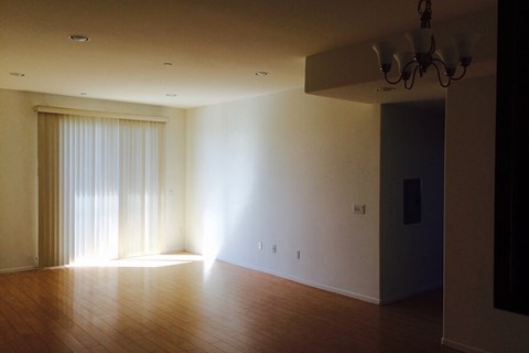 an empty living room with wood floors and a sliding glass door