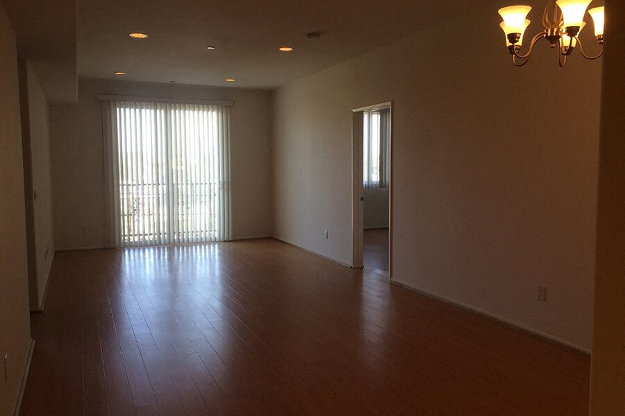an empty living room with wood floors and a door to a balcony
