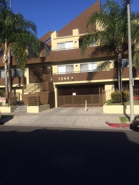 an apartment building with a driveway and palm trees