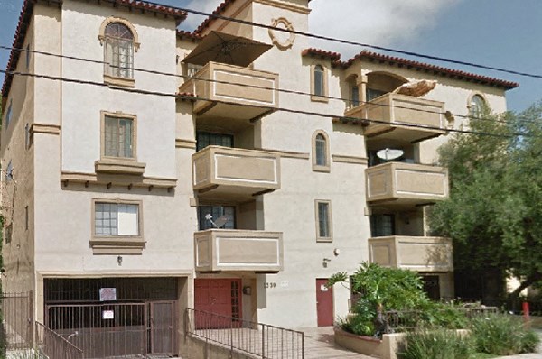 an apartment building with three balconies and a red door