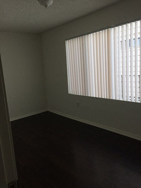 an empty room with a large window with white blinds