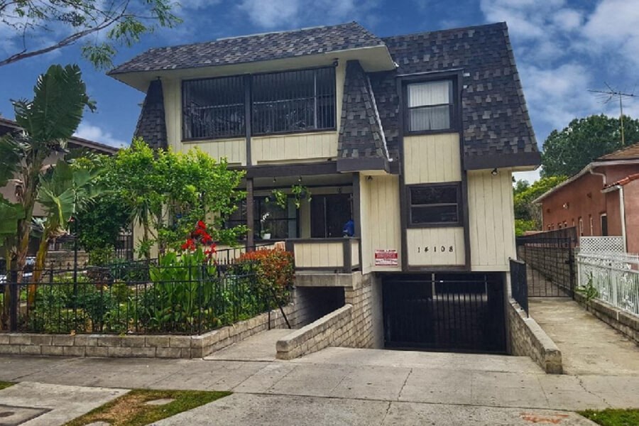 the front of a house with a driveway and a black gate