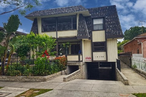 the front of a house with a driveway and a black gate
