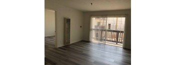 A room with a sliding glass door and a wood floor.