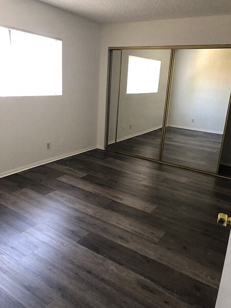 an empty living room with wood floors and a mirror