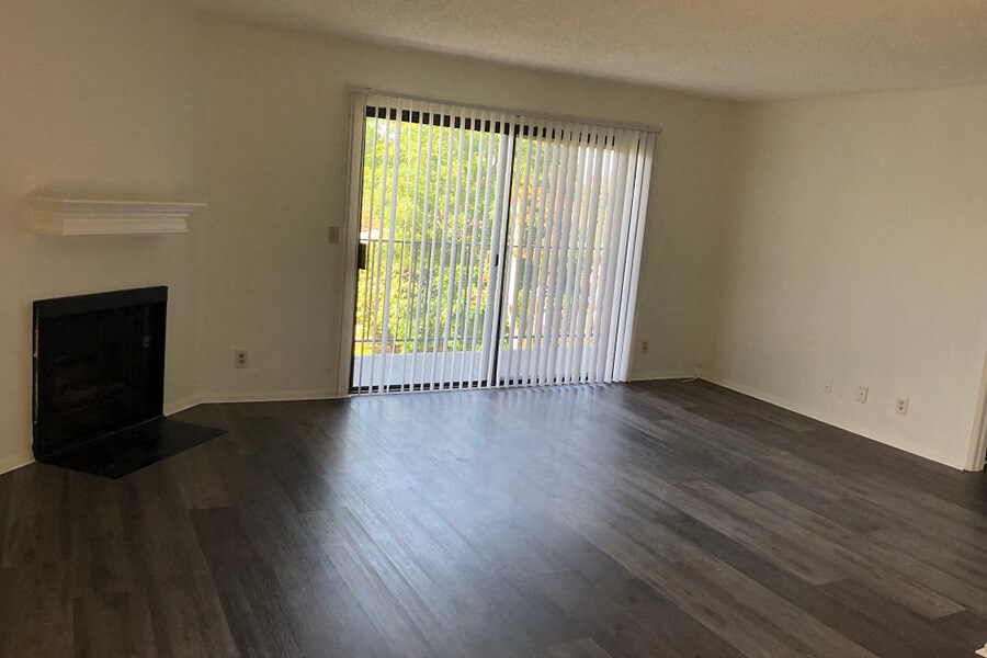 an empty living room with wood floors and a sliding glass door