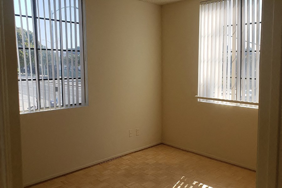 an empty room with two windows and a wooden floor