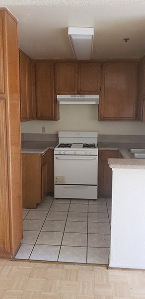 an empty kitchen with wooden cabinets and a white stove
