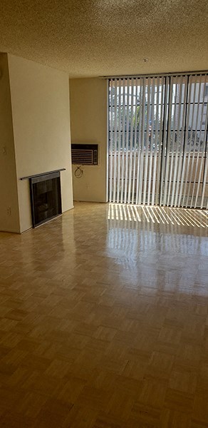 an empty living room with a fireplace and blinds on the window