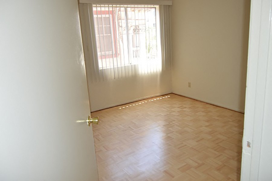 an empty room with wood flooring and a window