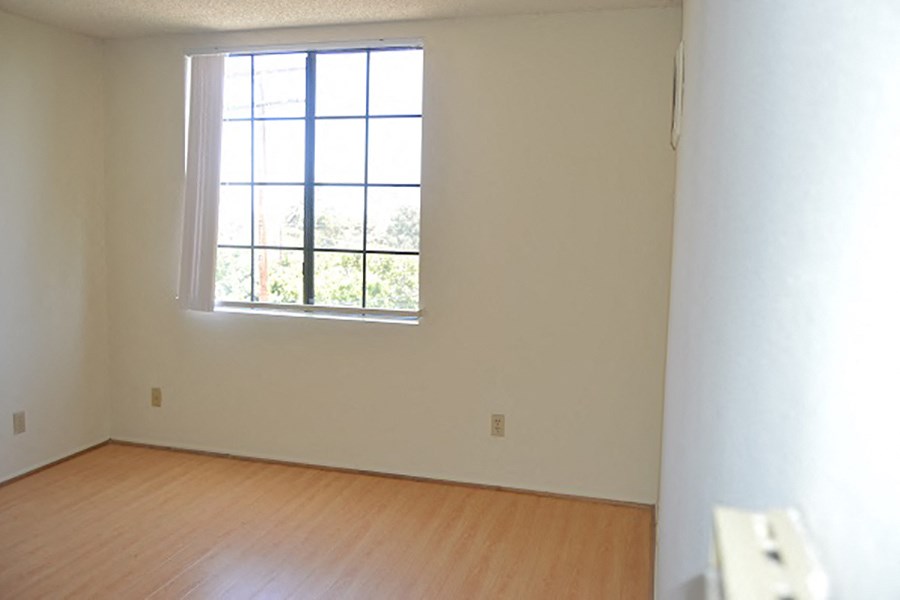 an empty living room with a window and wooden floors