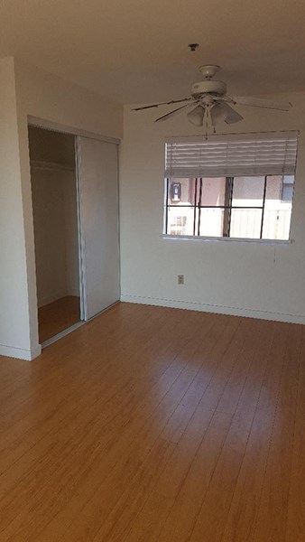 an empty living room with wood floors and a ceiling fan
