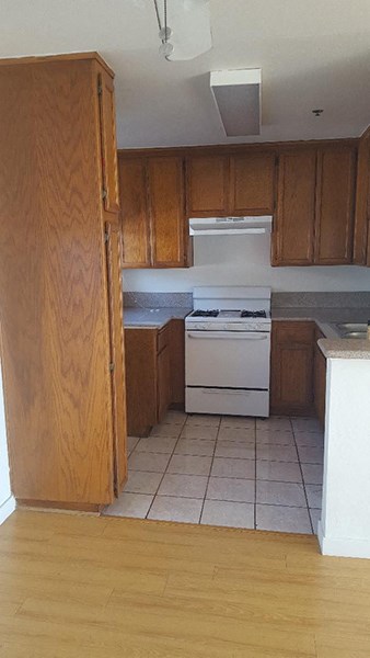 an empty kitchen with wooden cabinets and a white stove