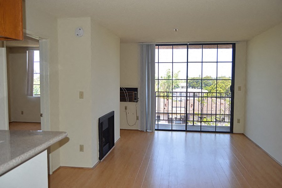 an empty living room with a sliding glass door to a balcony