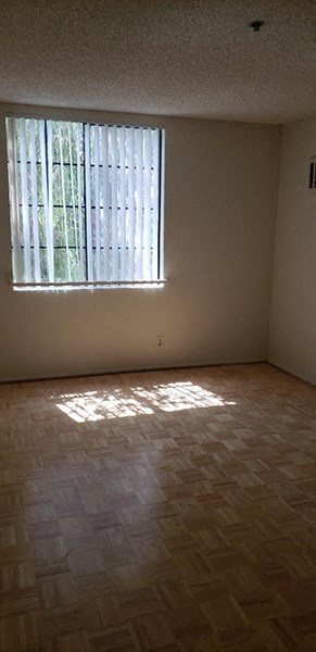 an empty room with a window and wooden floors