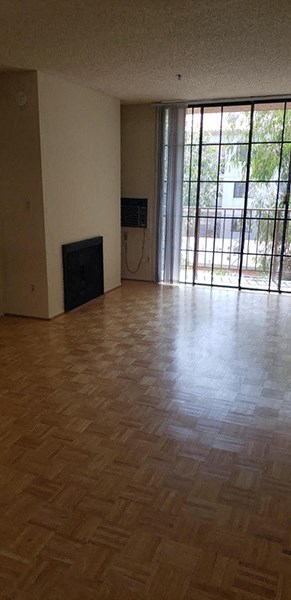 an empty living room with a wooden floor and a window