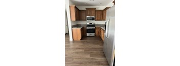 A kitchen with wooden cabinets and a stainless steel refrigerator.