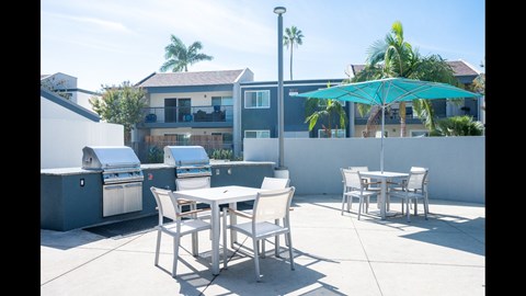 A patio with a table and chairs and an umbrella.
