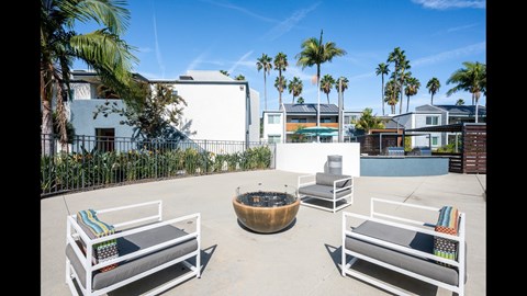 A patio with white furniture and a fire pit.