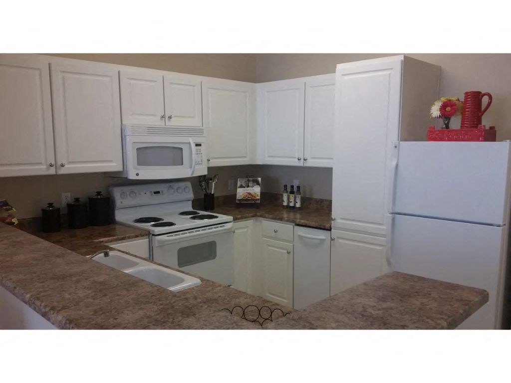 a kitchen with white cabinets and a white stove top oven  at Tesoro Senior Apartments, Porter Ranch, California