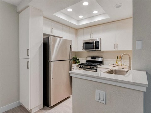 a kitchen with a refrigerator freezer next to a stove top oven  at Laguna Gardens Apts., California