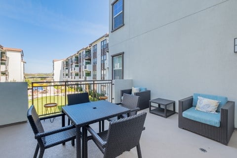A balcony with a table and chairs overlooking a pool at Deer Creek Senior Apartments in San Ramon, CA 94582