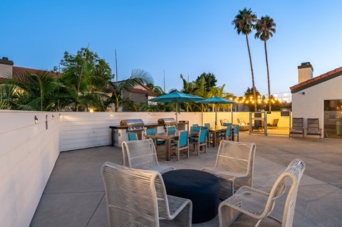 a rooftop patio with tables and chairs and palm trees at Laguna Gardens Apts., Laguna Niguel, California