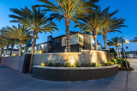 a sign in front of a building with palm trees  at Laguna Gardens Apts., Laguna Niguel
