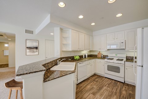 a kitchen with white appliances and granite counter tops and white cabinets