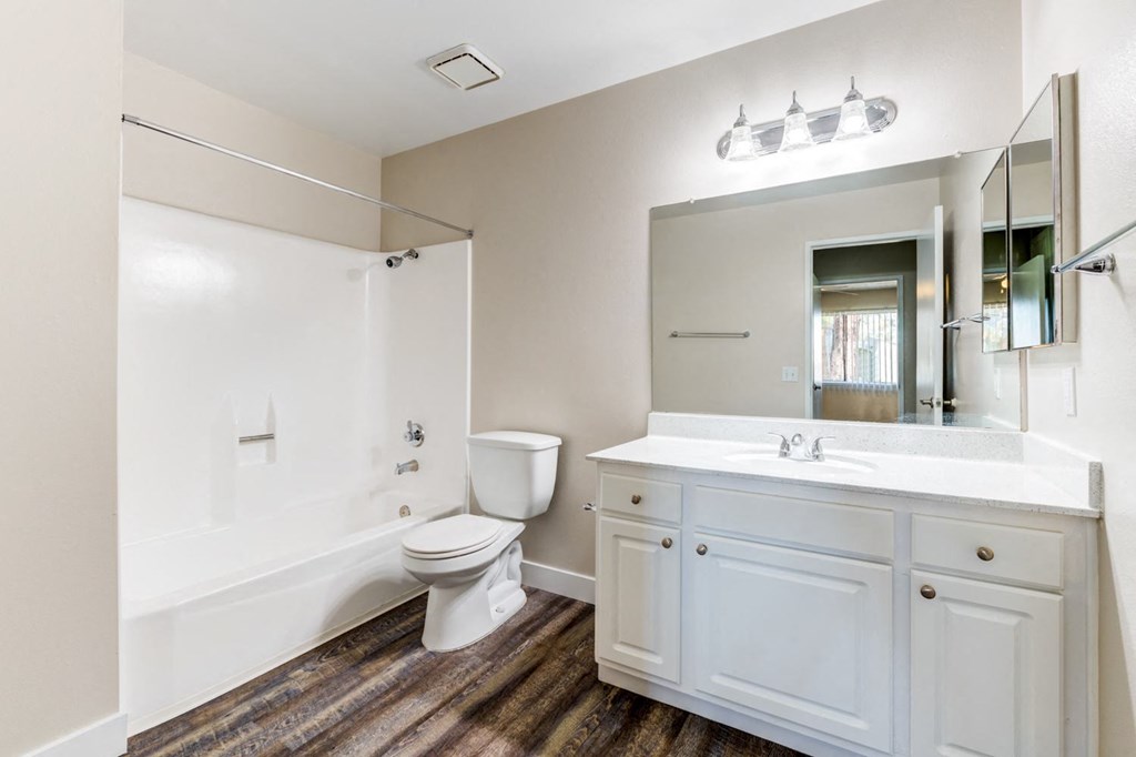 a bathroom with a toilet sink mirror and bathtub  at Redlands Park Apts, Redlands, 92373