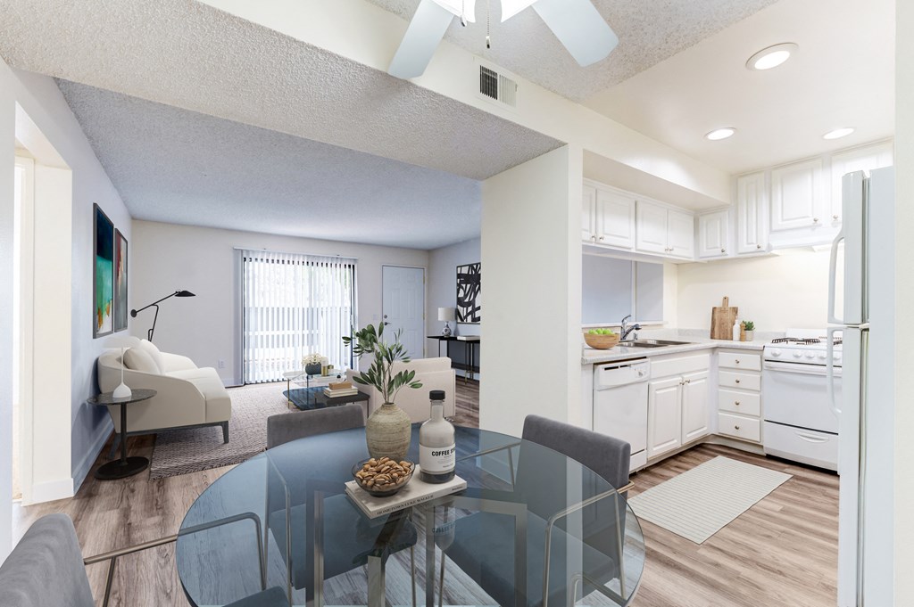 a living room with a glass table and a kitchen in the background a living room with a glass table and a kitchen in the background at Redlands Park Apts, Redlands, CA