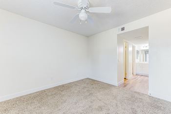 a bedroom with white walls and a ceiling fan
