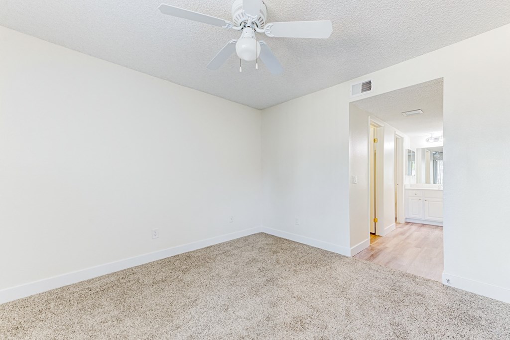 a bedroom with white walls and a ceiling fan  at Redlands Park Apts, Redlands, CA