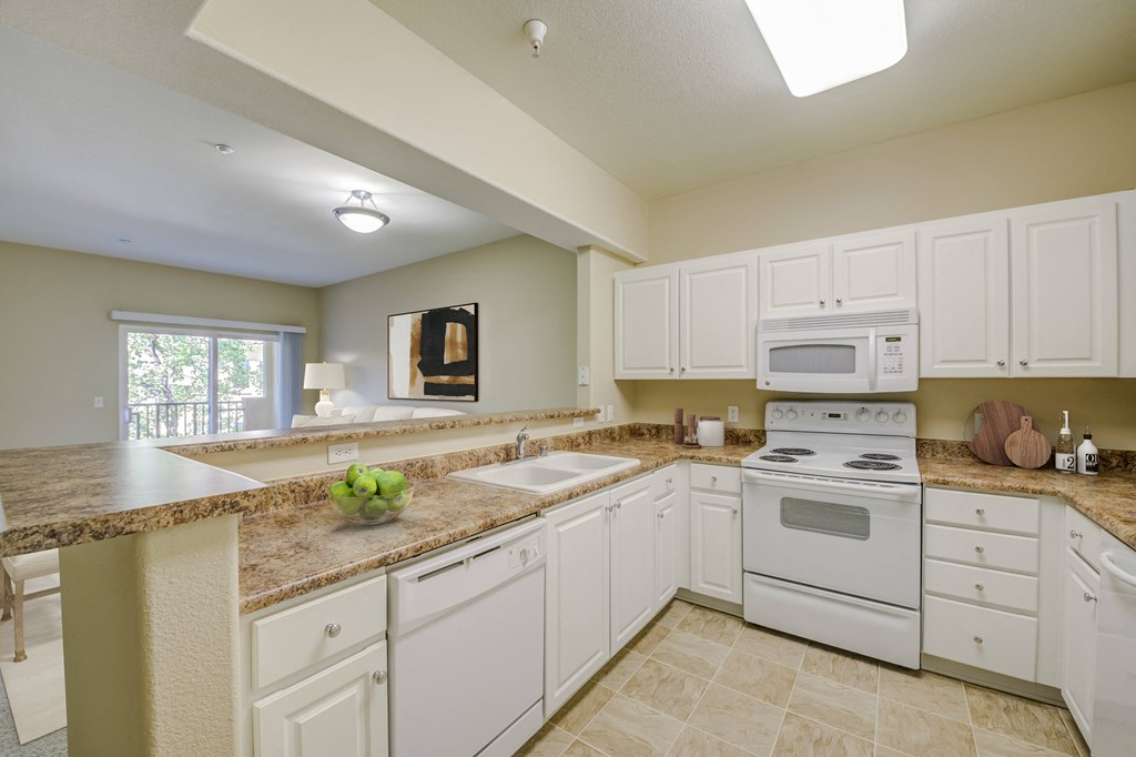 a kitchen with white cabinets and white appliances  at Tesoro Senior Apartments, Porter Ranch, CA